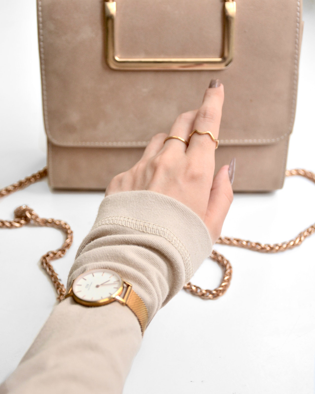 Handtasche mit Kette und Frauenhand mit Ringen und Uhr