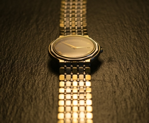 Goldene Uhr liegt auf dunklem Holz