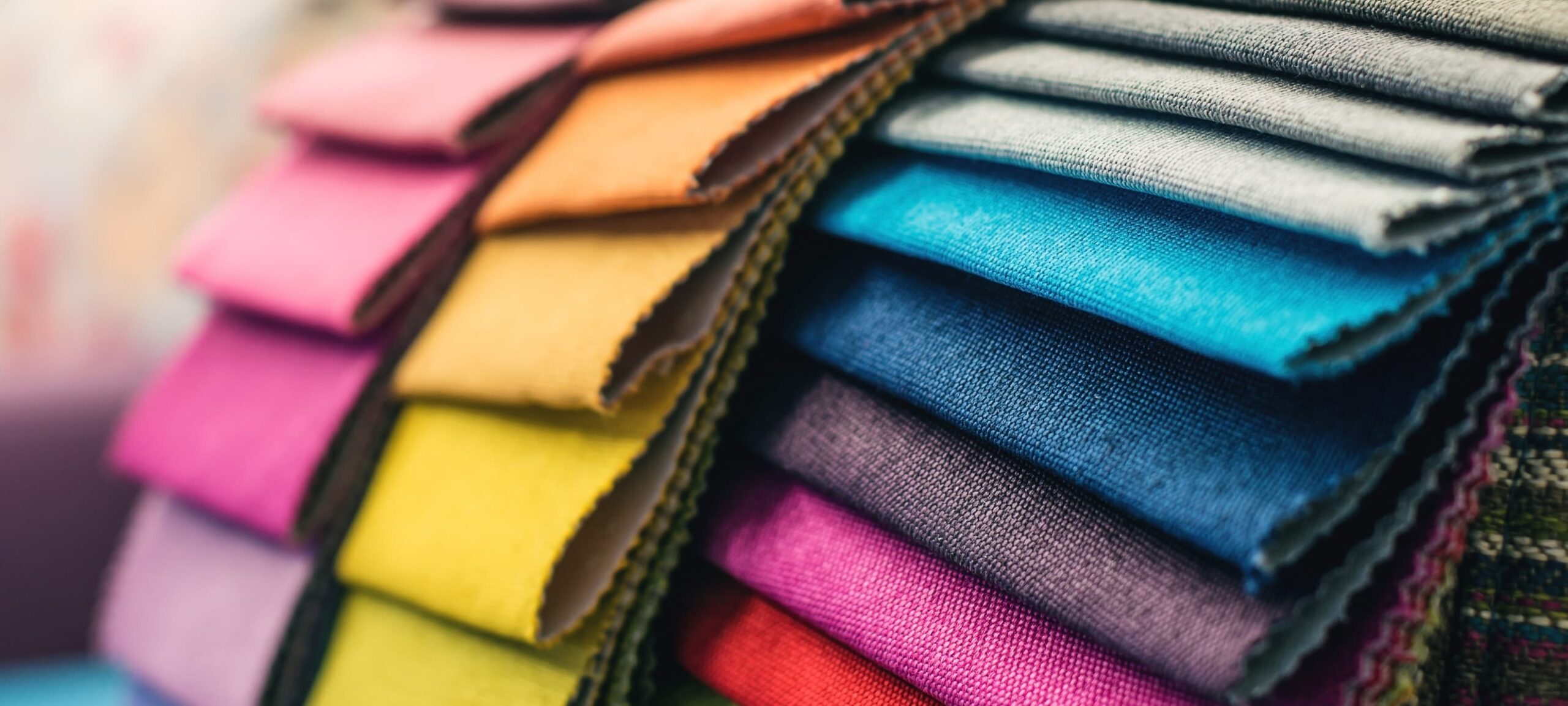 Drei aufgefächerte Stapel präsentieren Stoffe in verschiedenen Strukturen und Farben.