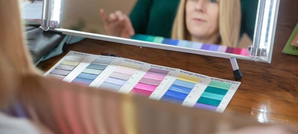 Mit Spiegel und Farbpalette suchen Kundin und Beraterin gemeinsam passende Farben zum Haar- und Hautton.