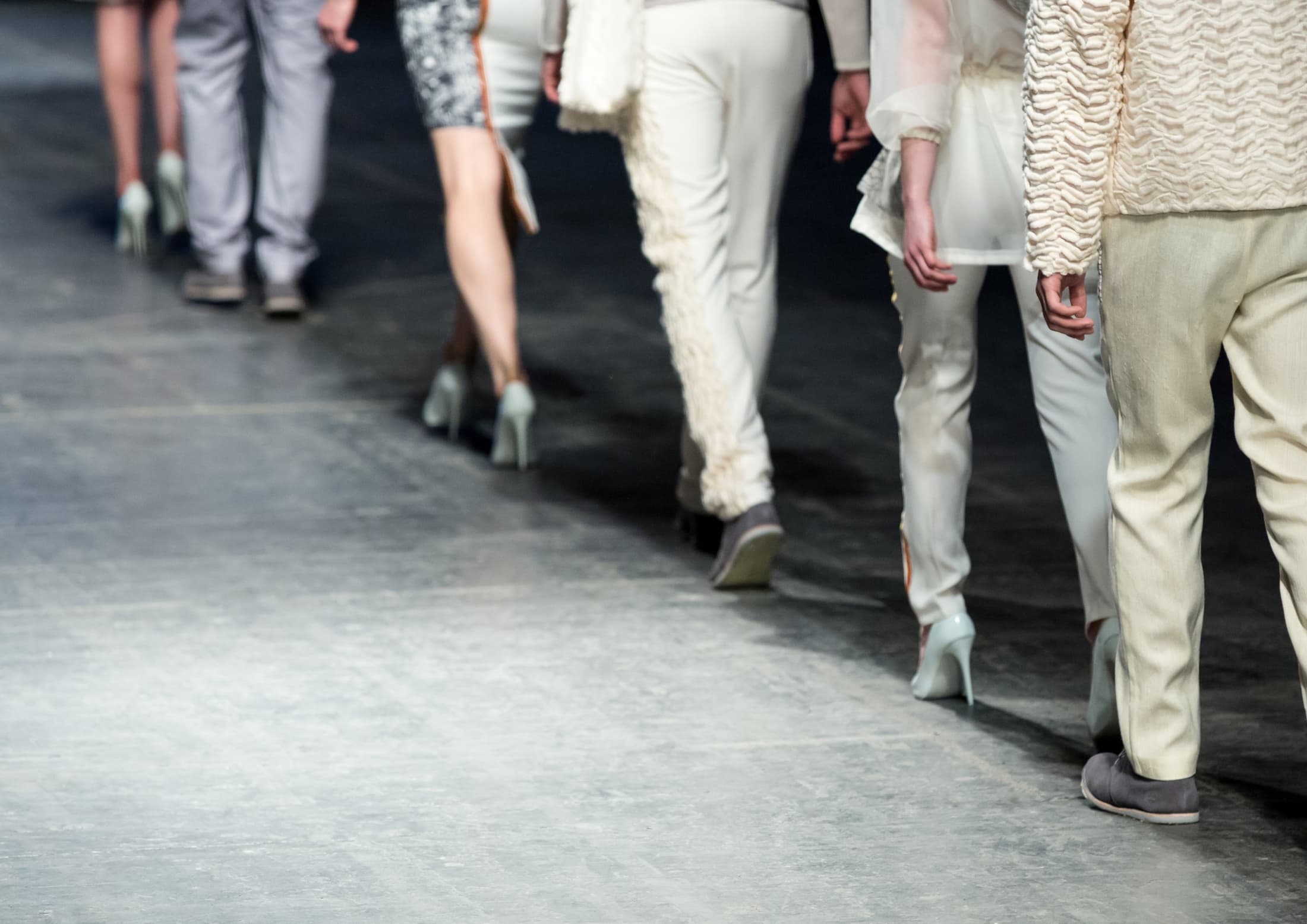Models pr&auml;sentieren Business-Looks am Laufsteg &ndash; helle Anzughosen und Bleistiftr&ouml;cke sowie hellblaue Stilettos und lederne Anzugschuhe.