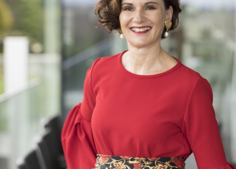 Eine elegante Dame tr&auml;gt die Powerfarbe Rot mit goldenen Akzenten.
